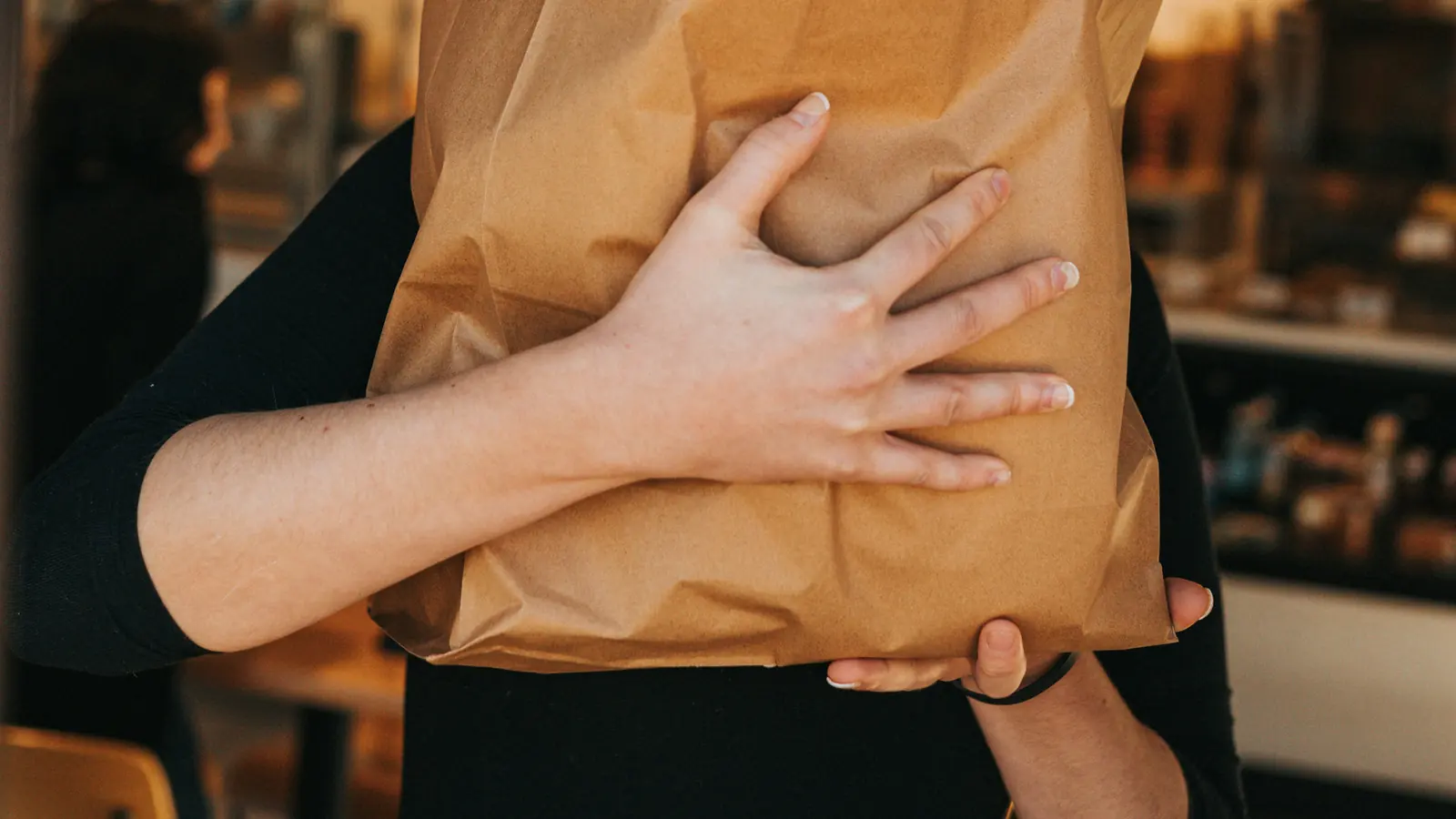 A Runner carrying a paper bag of shop items out to a customer.